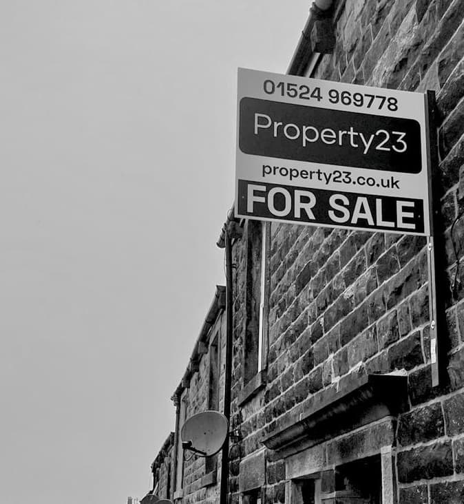 A Property23 'For Sale' board on a stone terraced house